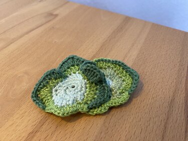 Nahaufnahme von zwei gehäkelten Avocadohälften auf Holzuntergrund