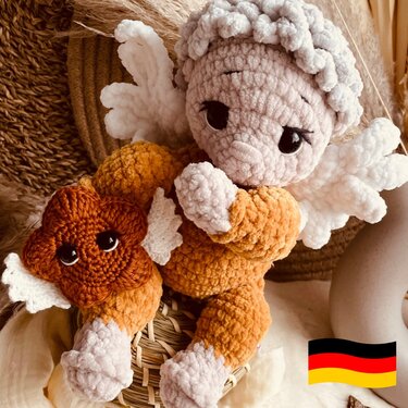 Gehäkelter Amigurumi-Engel in beige und orange mit weißen Flügeln und großen dunklen Augen