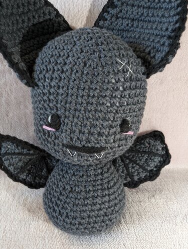 Kuscheliges dunkelgraues Fledermaus-Amigurumi mit gestickten Augen und Zähnen