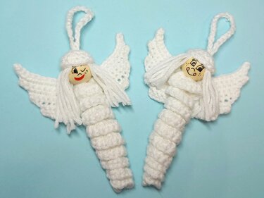 Zwei weiße gehäkelte Engel-Anhänger mit Holzperlenköpfen und Aufhängeschlaufen auf hellblauem Hintergrund