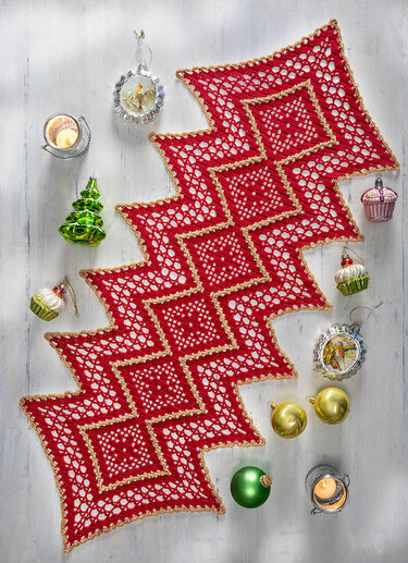Roter gehäkelter Tischläufer mit goldener Borte auf hellem Holztisch, umgeben von Weihnachtskugeln und Kerzen
