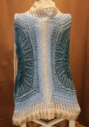 Rückenansicht einer langen gehäkelten Damenweste in Blau und Creme mit Rippen- und Kreisornamenten