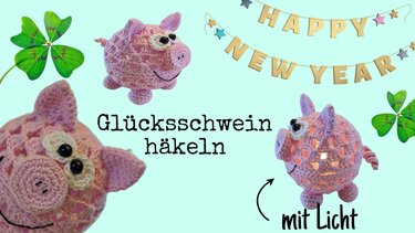 Rosa gehäkeltes Glücksschwein in Kugelform mit leuchtendem Innenraum, Nahaufnahmen und ‚Happy New Year‘-Girlande