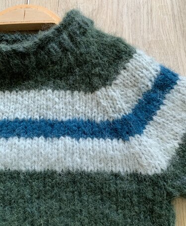 Nahaufnahme eines gestrickten Kinderpullovers mit hohem, geripptem Kragen in Dunkelgrün und horizontalen Streifen in Hellgrau und Dunkelblau.