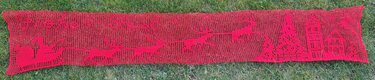Roter gehäkelter Tischläufer mit Rentiermotiv auf Gras, Draufsicht