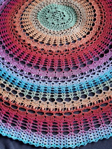 Rundes gehäkeltes Deckchen mit konzentrischen Spitzenmustern und mehrfarbigem Farbverlauf