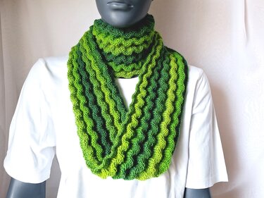 Gestrickter Loop‑Schal in Grüntönen mit Wellenmuster an Schaufensterpuppe