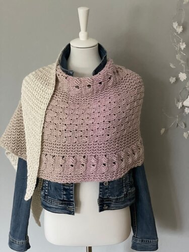 Hellrosa halbrundes Häkeltuch mit Lochmuster über einer Jeansjacke an einer Schaufensterpuppe.