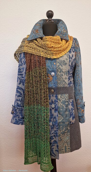 Gehäkelter Ombre-Schal in Gelb, Braun und Grün, um einen Mantel drapiert