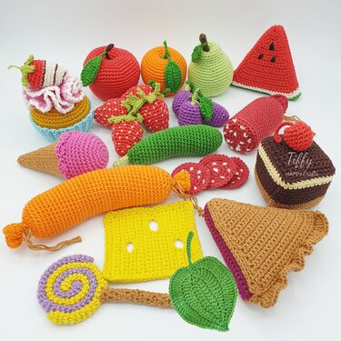 Colorful crocheted play food items arranged on a white background.