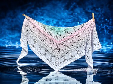 Triangular crochet shawl pinned at the top corners, showing repeating lace motifs and border