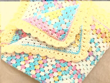 Gehäkelte Babydecke mit Granny-Square-Muster in Pastell und gelbem Wellenrand