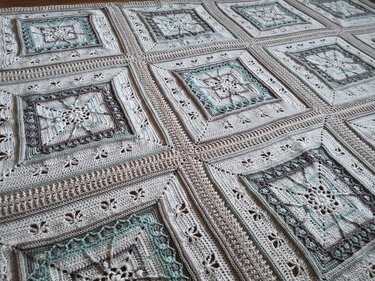 Gehäkelte Decke aus verbundenen Quadraten in Beige, Grau und Mint mit sternförmigen Mustern und Bordüren.
