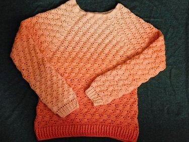 Ombre crochet sweater in peach and coral laid flat, showing textured stitch pattern