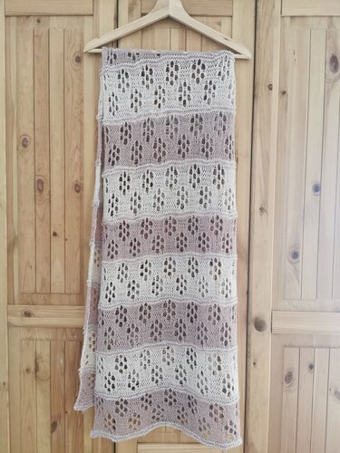 Gestricktes Lacetuch beige und lila mit Lochmuster auf Holzhintergrund