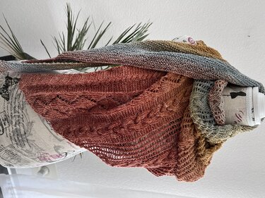 Gestricktes Dreieckstuch mit Farbverlauf (Terrakotta–Blaugrau–Gold), Zopf- und Ajourmuster, drapiert