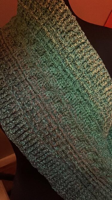 Nahaufnahme eines gehäkelten Loop-Schals in Türkis- und Grüntönen mit geripptem Strukturmuster.