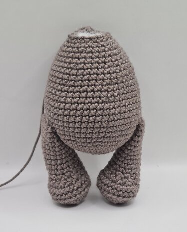 Gehäkelter Amigurumi-Rumpf mit zwei angenähten Beinen und sichtbarer Füllwatte