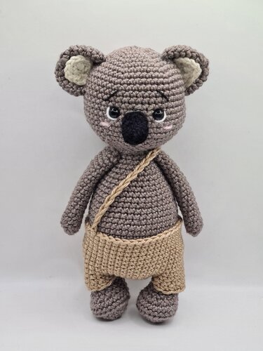 Gehäkelter grauer Koala-Amigurumi mit hellbeiger Hose und Umhängetasche, stehend