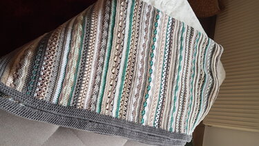 Gehäkelte Decke mit schmalen Streifen in Creme, Grau und Mint, mit grauer Einfassung, auf einem Sofa drapiert