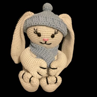 Weißer gehäkelter Amigurumi-Hase mit langen Ohren, hellblauer Mütze und Schal