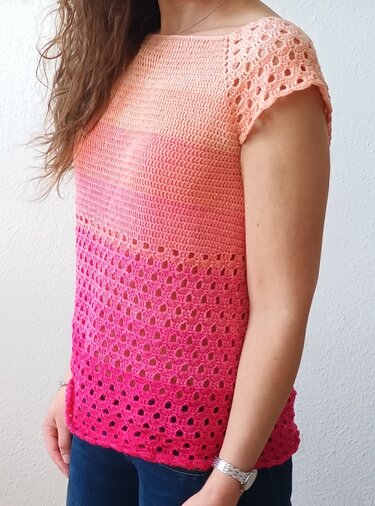 Kurzärmeliges gehäkeltes Damenshirt mit Farbverlauf von Peach zu Fuchsia und dekorativem Lochmuster im unteren Bereich.