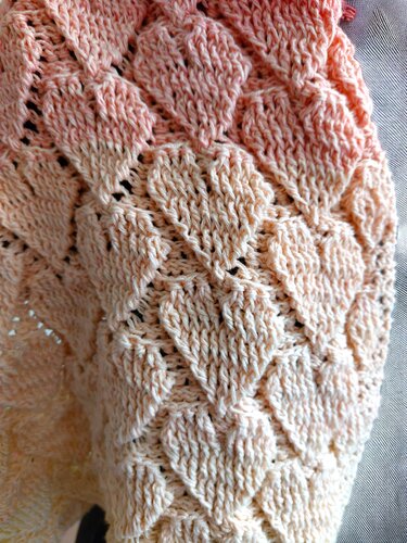 Macro photo of heart lace stitch pattern on a crochet loop scarf in peach yarn