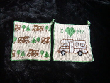 Zwei gehäkelte quadratische Topflappen beige mit grüner Kante; links wiederholtes Wohnmobil- und Baum-Muster, rechts einzelnes Wohnmobil mit Herz und Schlaufe