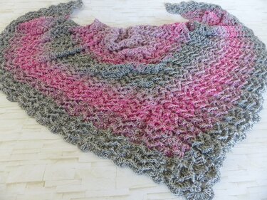 Gehäkeltes Dreieckstuch in Rosa und Grau mit offenem Muschelmuster liegend