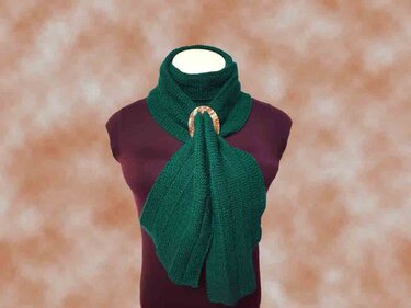 Gestrickter grüner Schal mit rundem Holzring auf einer Schaufensterpuppe