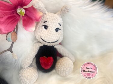 Gehäkeltes Amigurumi-Insekt beige mit schwarzem Körper und rotem Herz
