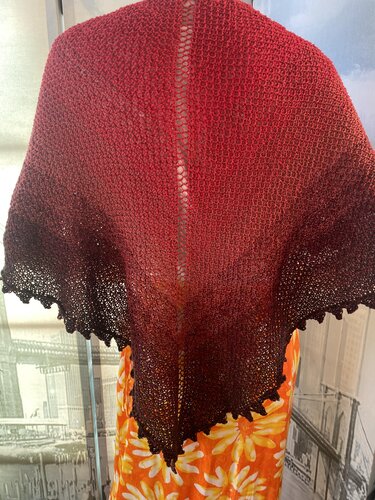 Red-to-brown gradient triangle shawl with ridged body and scalloped lace edge draped on a dress form