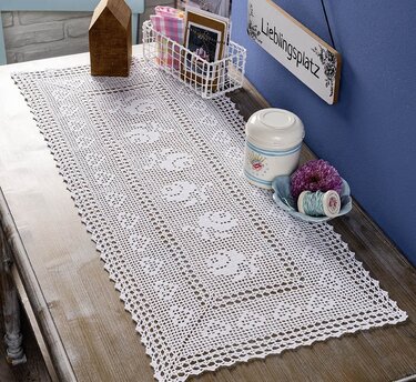 Weißer gehäkelter Filet-Tischläufer mit Blumenmotiv und Spitzenrand auf Holzsideboard