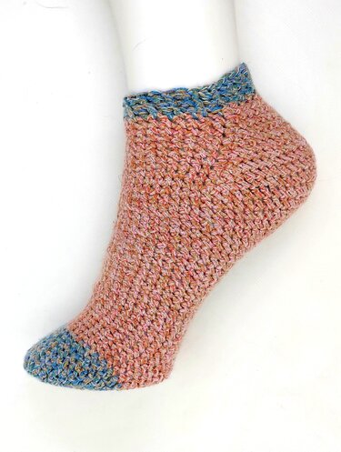 Gehäkelter Kurzsocken-Füßling in Rosa und Blau auf weißem Fußmodell