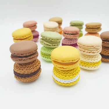 Assorted pastel crochet macarons stacked on a white background