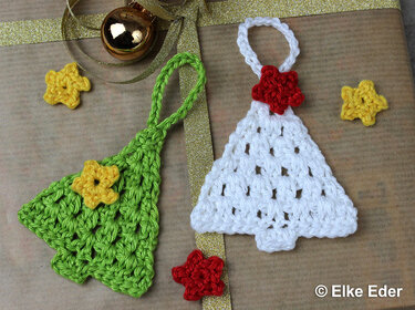 Green and white crocheted Christmas tree ornaments with small star embellishments on a wrapped gift.