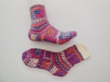 Paar handgestrickter bunter Damensocken in Patchmuster, eine auf Leiste mit Größe 36/37