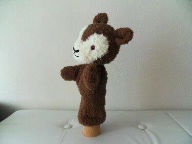 Gestrickte braun-weiße Reh-Handpuppe auf hellem Untergrund