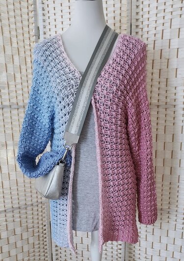 Schaufensterpuppe mit gehäkelter, offener Damenjacke in Blau‑Weiß‑Rosa Farbverlauf