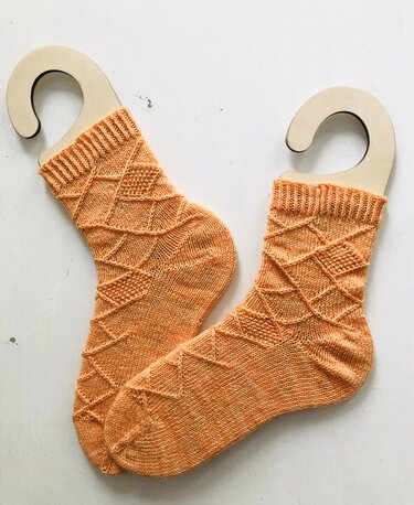 Orange gestrickte Socken mit Rautenmuster auf Holz-Sockenspannern