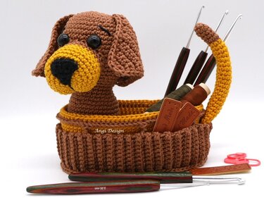 Gehäkelter Aufbewahrungskorb in Hundeform mit sichtbaren Häkelnadeln und Garn