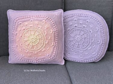 Quadratisches Farbverlaufskissen und rundes lila Kissen mit Mandala-Muster auf grauem Sofa
