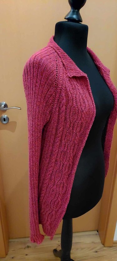 Pinkfarbene Strickjacke mit Zopf- und Rippenmustern auf schwarzer Schneiderpuppe