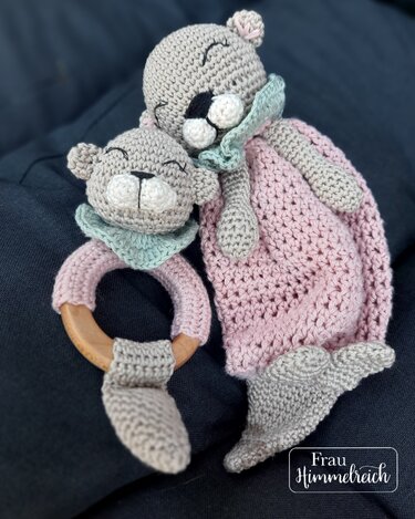 Gehäkeltes Bären-Schmusetuch in Rosa und Grau mit passendem Beißring mit Holzring, beide mit schlafendem Bärengesicht.
