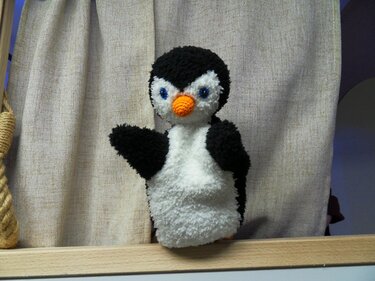 Schwarz-weiße flauschige Pinguin-Handpuppe mit blauen Augen und orangefarbenem Schnabel