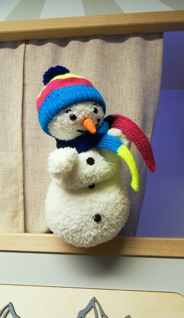 Gestrickter Schneemann-Amigurumi mit gestreifter Mütze, Schal und schwarzen Knöpfen