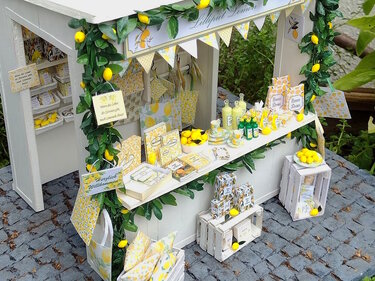 Bastelstand in Miniatur mit Zitronenmuster, Papiertüten und weißen Miniaturkisten