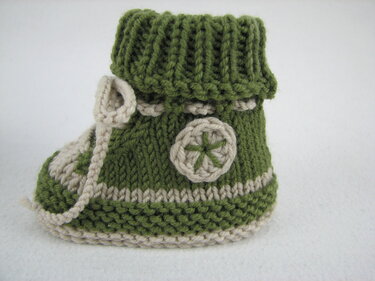 Grüner gestrickter Babyschuh mit beiger Kontrastkante, Rippbündchen und Schnürband