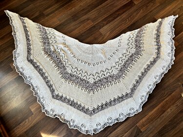 Halbrundes gestricktes Tuch mit Ajourmuster und gezackter Kante auf Holzboden