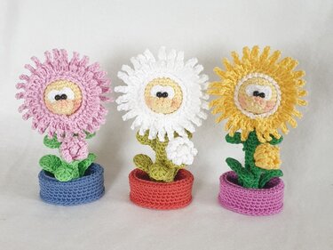 Drei gehäkelte Blumen in kleinen Töpfen mit süßen Gesichtchen (rosa, weiß, gelb)